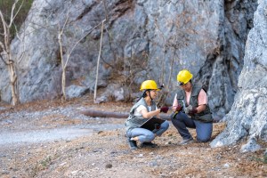 Two Female geologists working in the field Rock and mineral exploration in natural environments. Scientific teamwork in geological research study data by observation rock inspection on mountain. Two Female geologists working in the field Rock and mineral exploration in natural environments. Scientific teamwork in geological research study data by observation rock inspection on mountain.